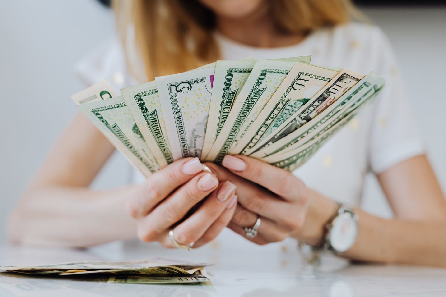 woman holding fan of dollar bills